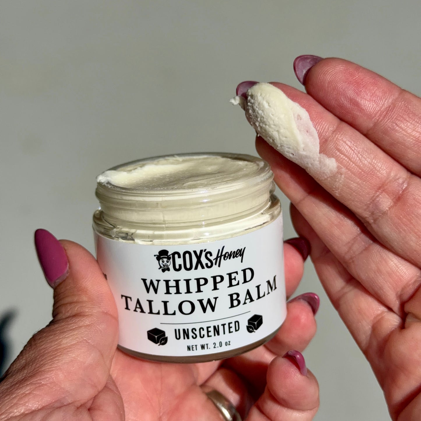 Cox's Honey Whipped Tallow Balm jar with a hand applying balm.