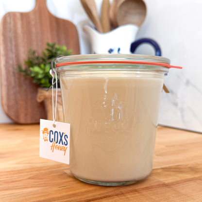 Weck Glass Jar of creamed honey with a Coxs Honey tag on a wooden surface