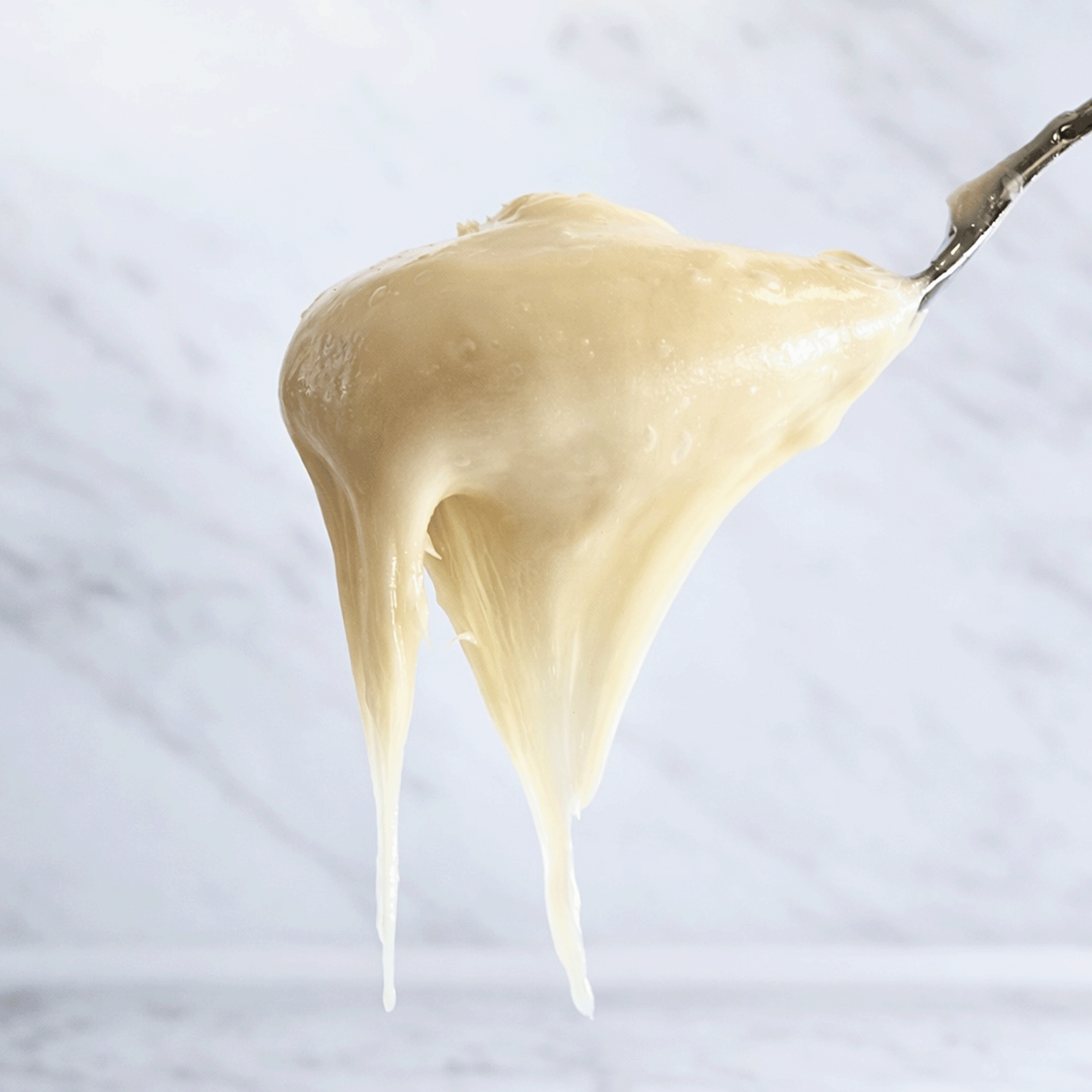 Cream Honey no drip from a spoon onto a light gray background
