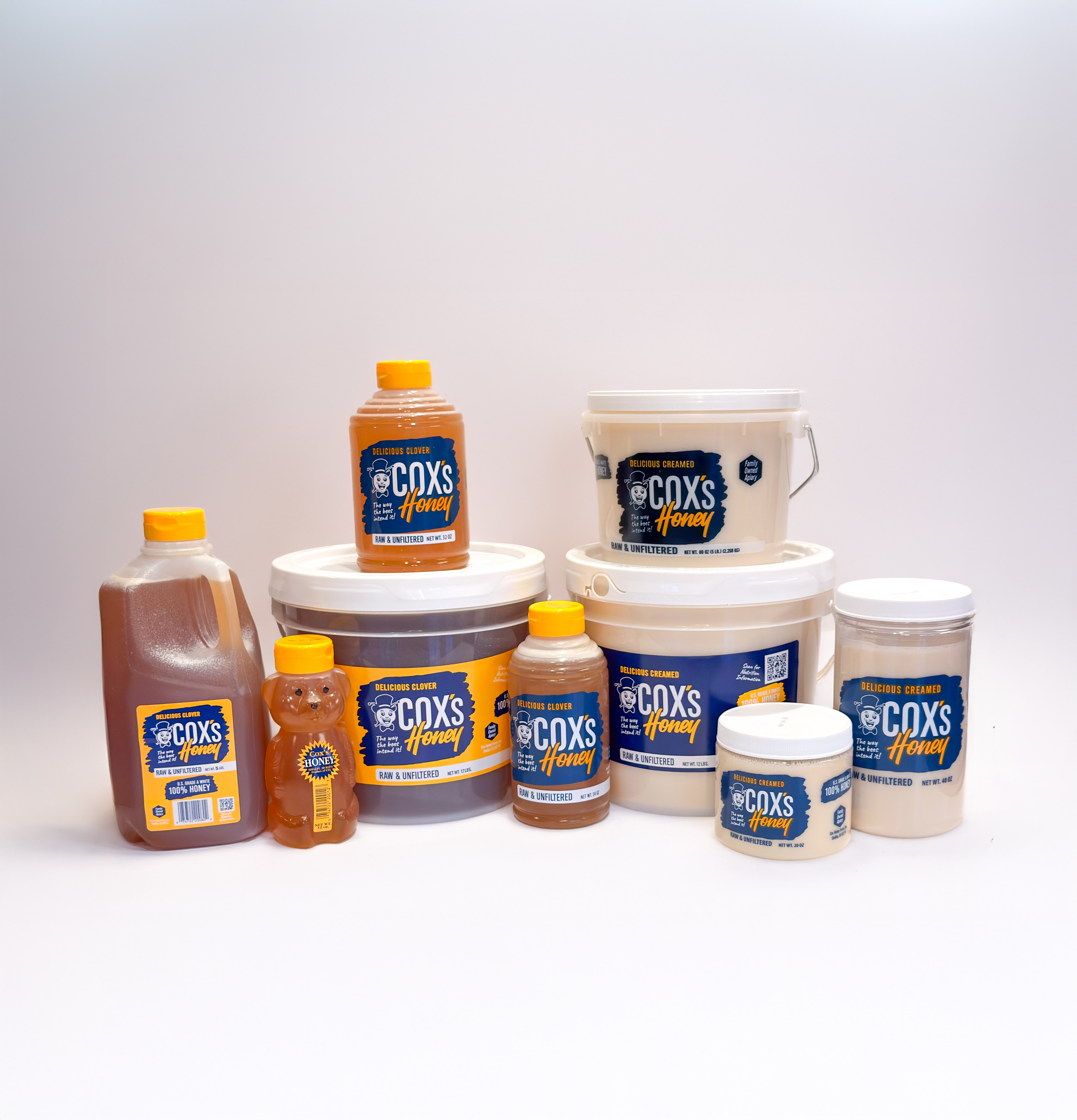 Assorted Cox's Honey products including bottles and buckets on a white background