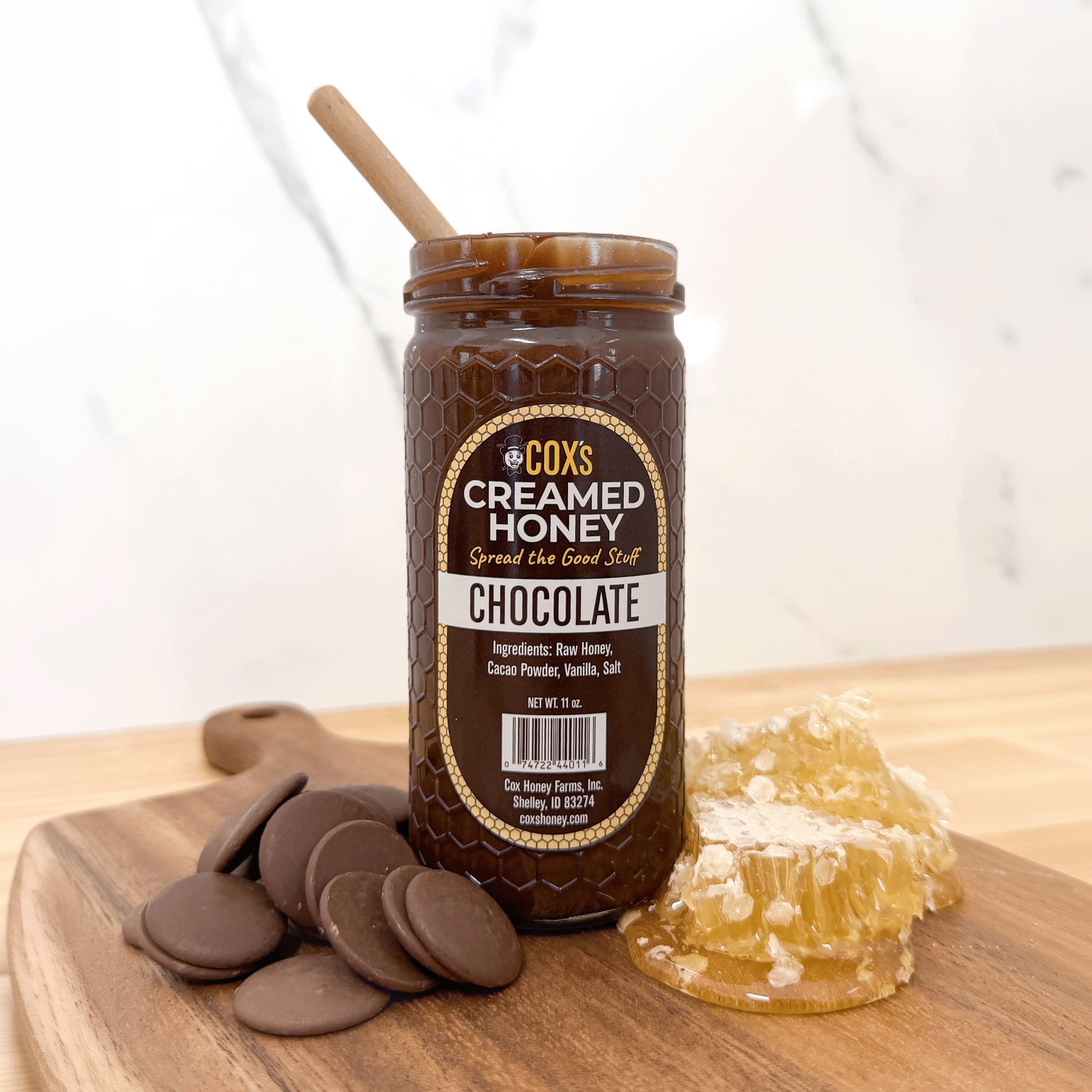 Jar of Cox's Creamed Honey Chocolate on a wooden surface with honeycomb and chocolate pieces.