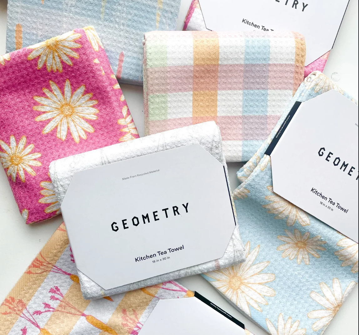 Set of colorful kitchen tea towels with 'Geometry' branding on packaging.
