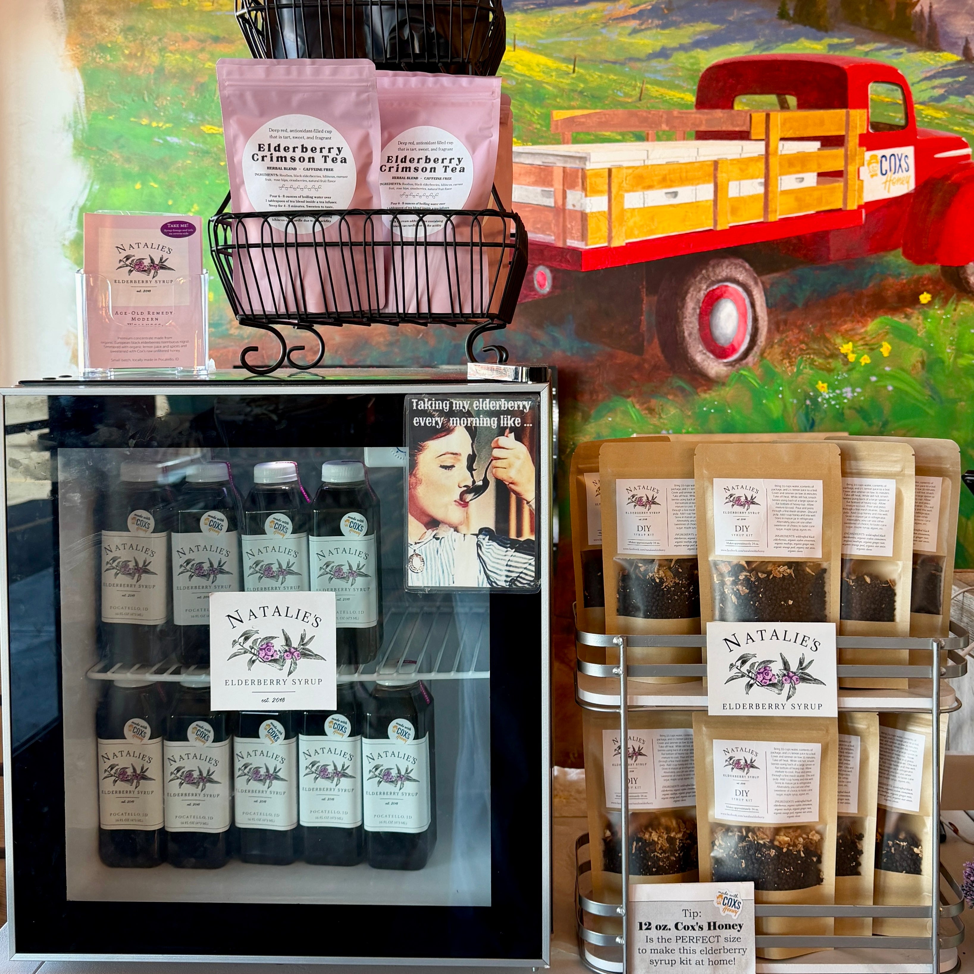 Display of Natalie's Elderberry products including bottles, bags, and a red truck in the background.