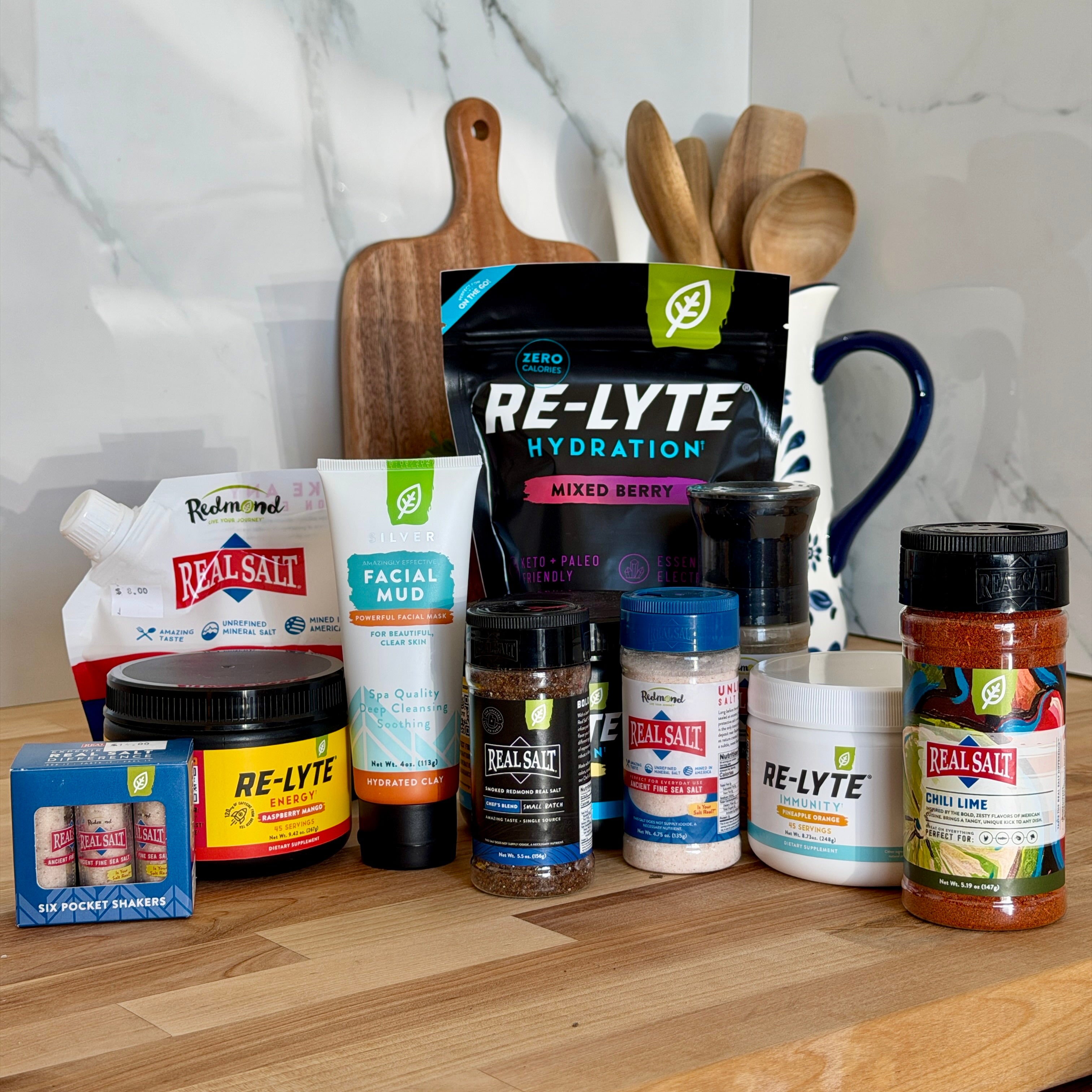 Assorted health and wellness products on a kitchen counter with a marble wall background.