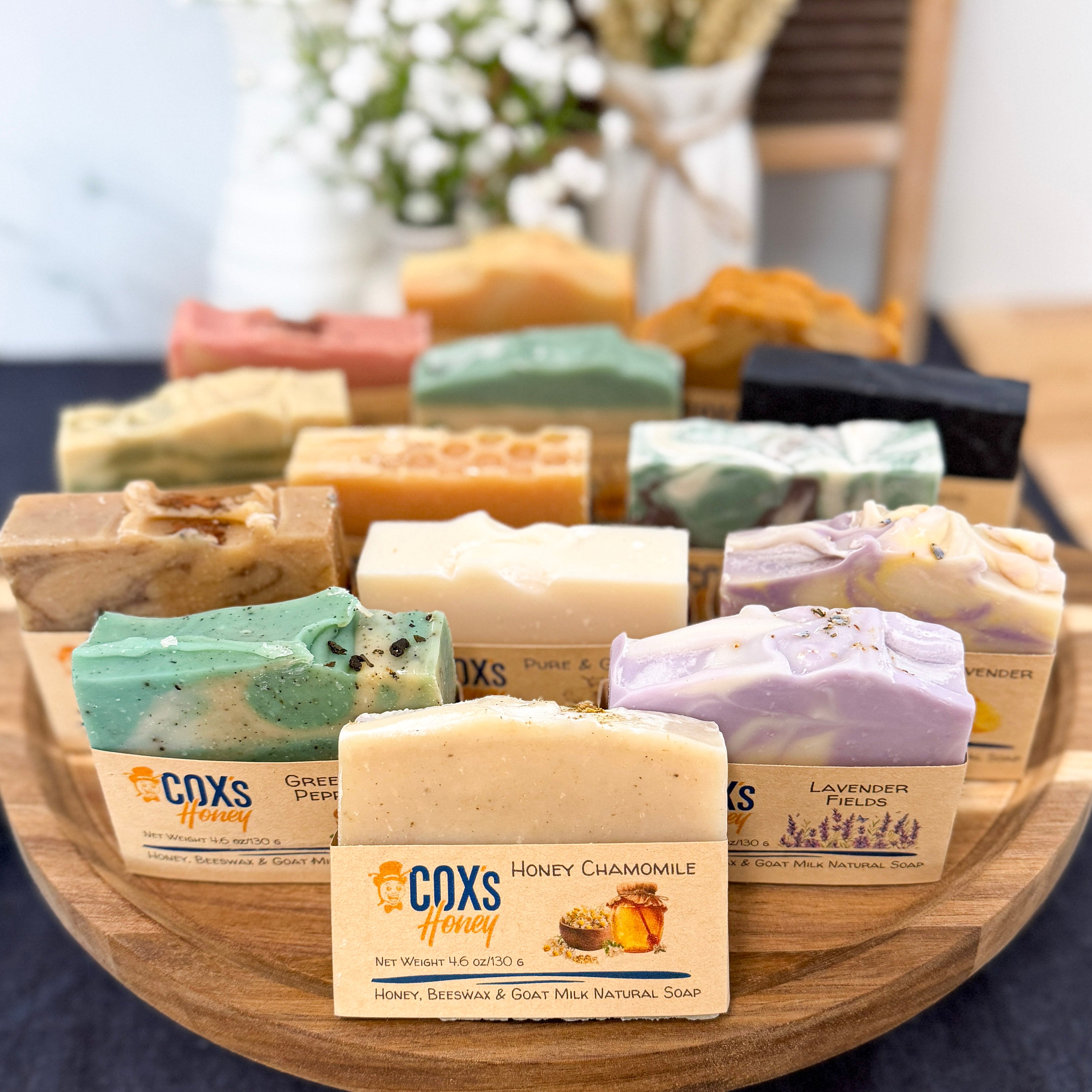 Assorted Coxs Honey soaps on a wooden tray with a blurred background