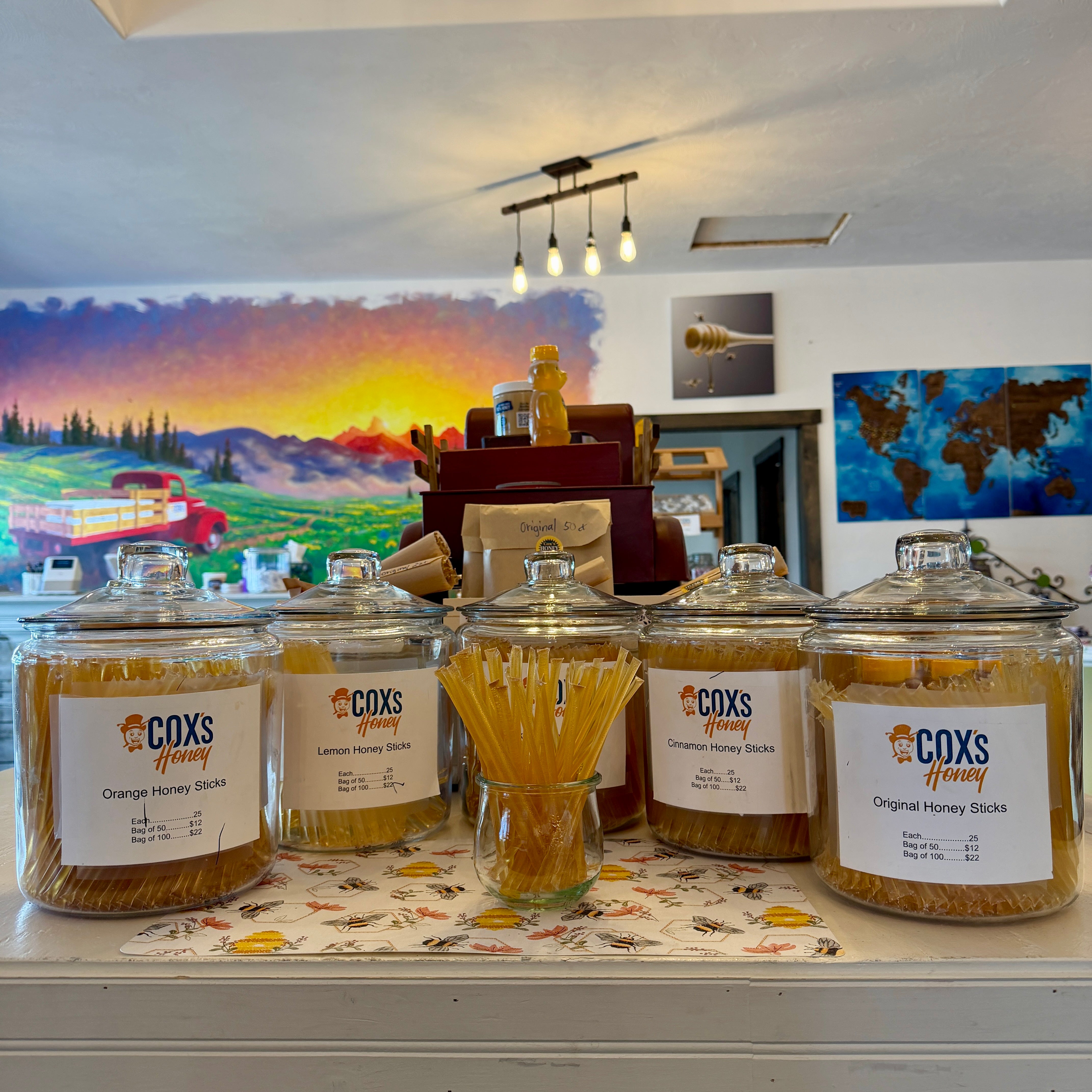 Jars of Coxs honey on a counter with a colorful mural in the background