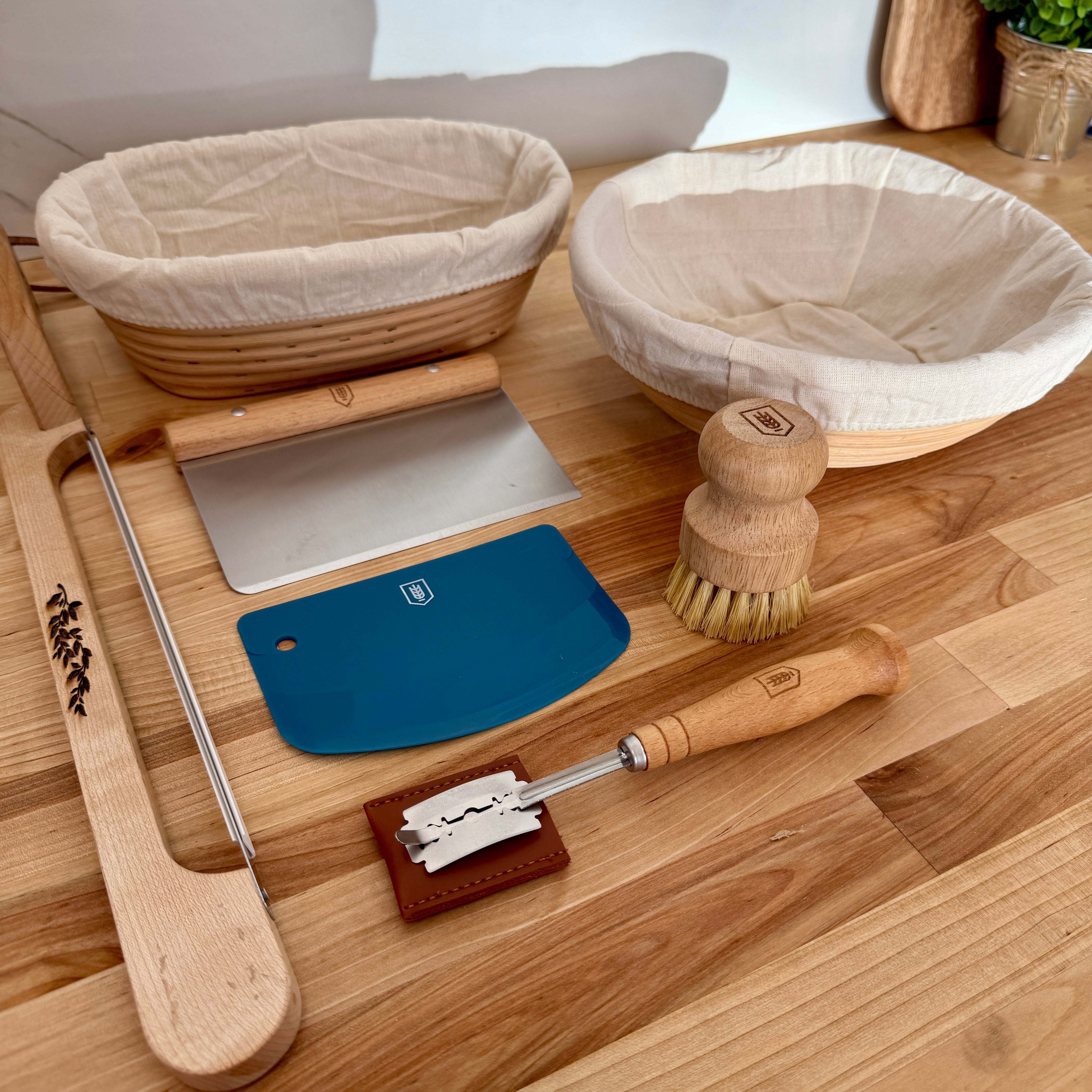 Baking tools including a dough scraper, bench scrapper, and rolling pin on a wooden surface.