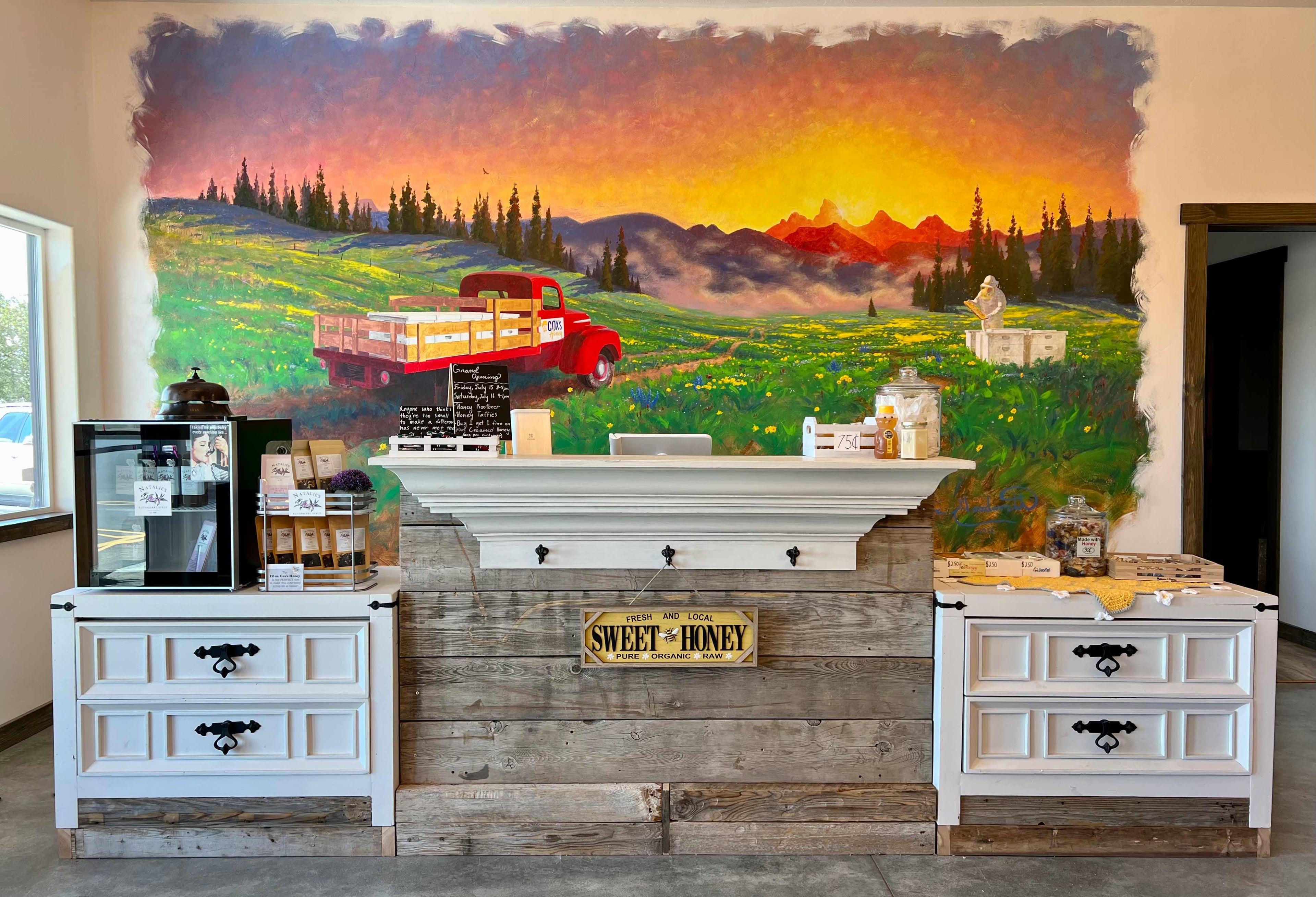 Coxs Honey checkout stand at our current store. With a old painting on the wall of a work truck with bees hives on the bed with a guy working the bees.